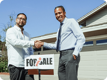 Handshake in front of a sold sign
